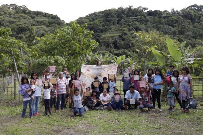 Mulheres e crianças indígenas exibem peças produzidas durante as oficinas de tingimento natural e pintura em tecido, realizada pelo Projeto Cores da Terra, em Abril, Maio e Junho de 2023, em Araquari (SC). Crédito: Acervo Instituto Muhda.